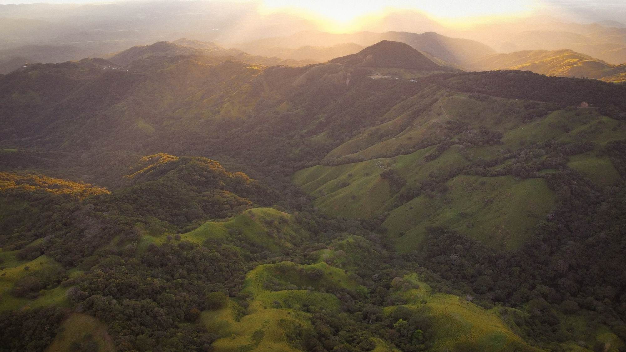 Aerial view of lush green Costa Rican mountains at golden sunset.