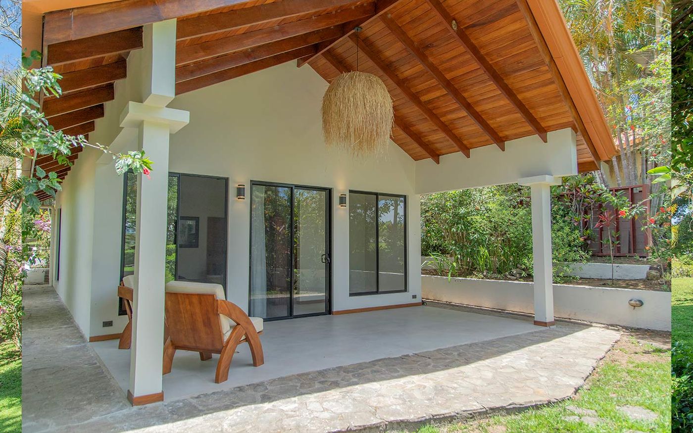 The private porch outside one of the porch rooms. Wood-beamed ceiling, sliding doors into the room, and a view across the gardens.