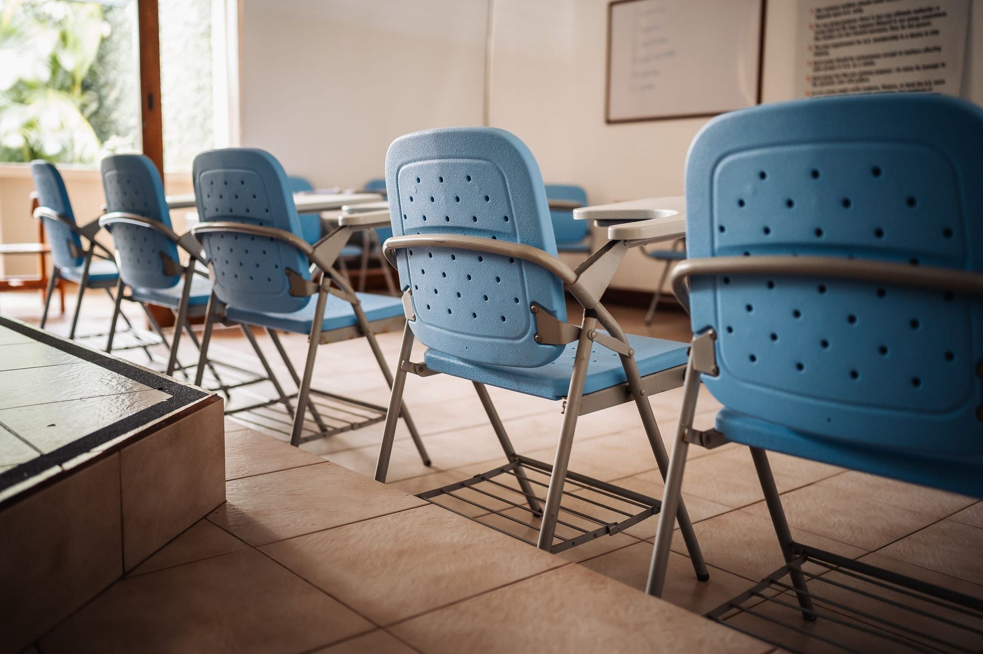 A row of blue chairs in the group room at San José, lit by the windows.