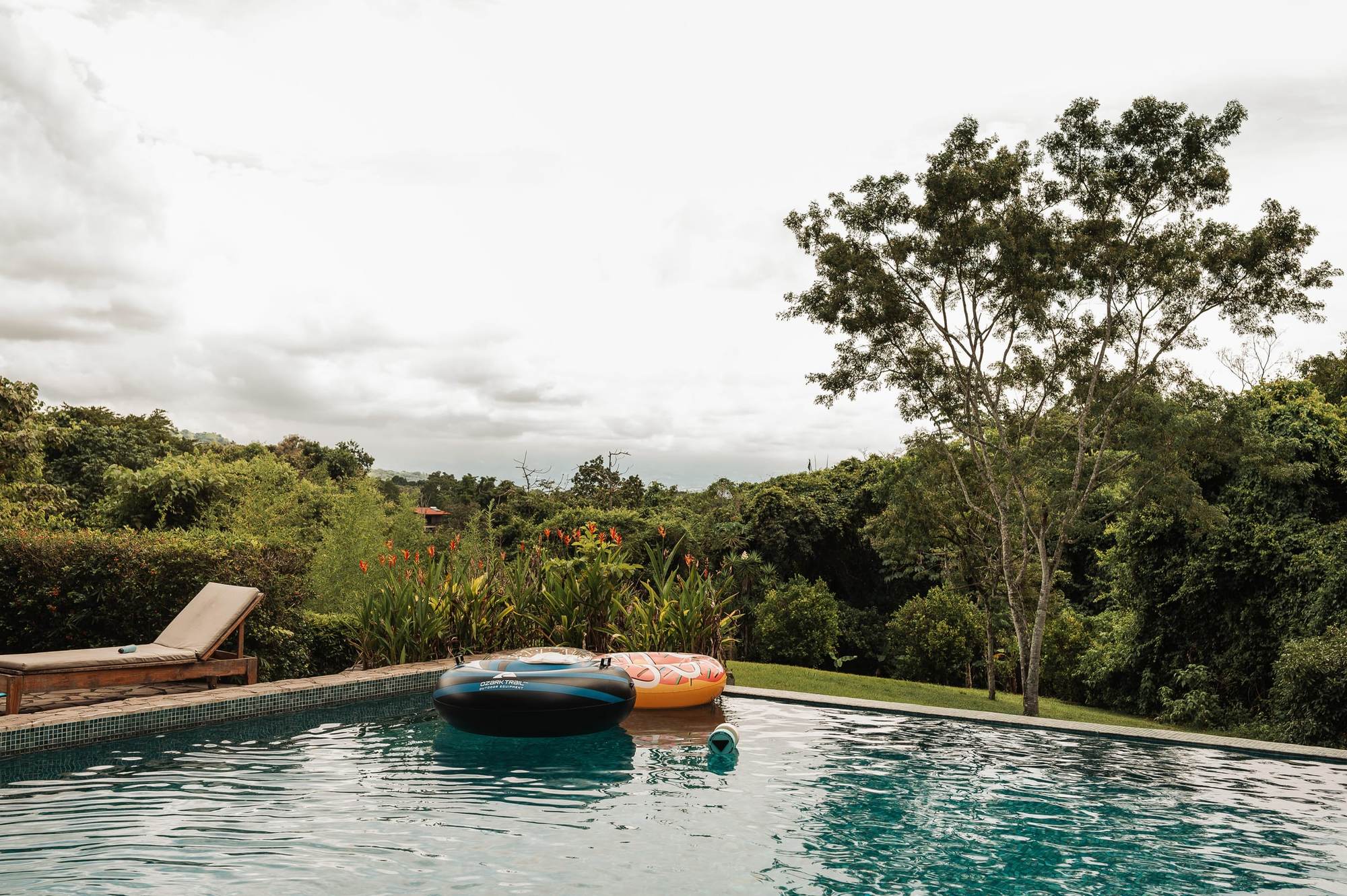 The turquoise infinity pool at Atenas, with dense green trees beyond its edge.