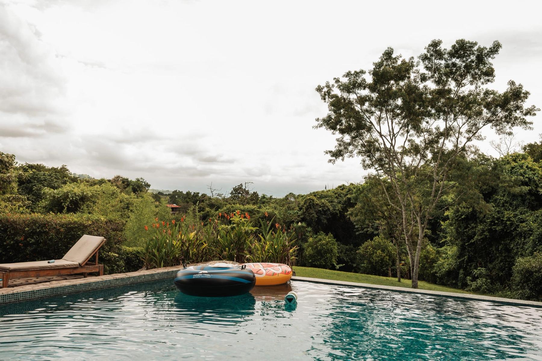 The infinity pool at Atenas, with loungers and floats, looking out over the forest.