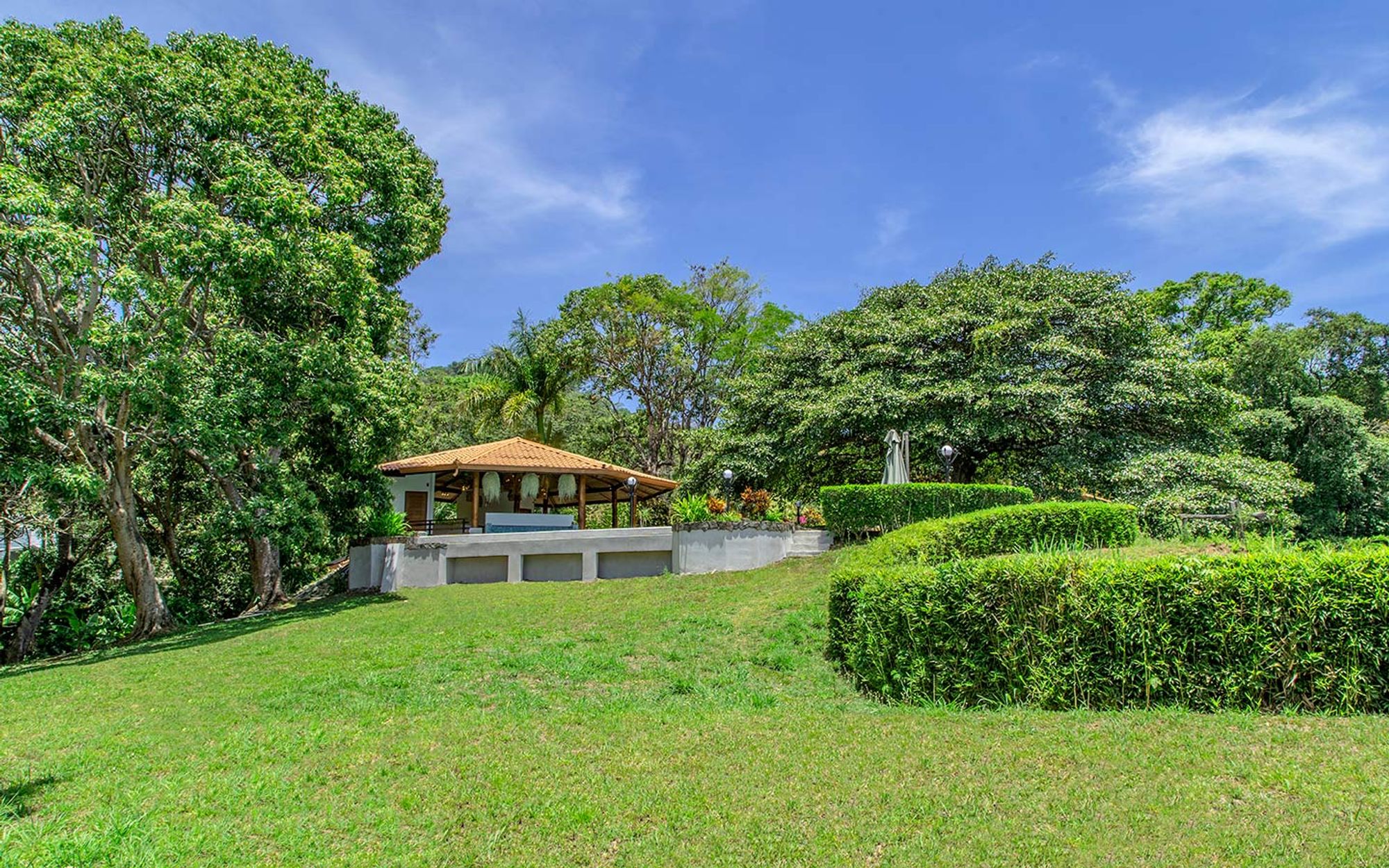 Tropical gardens with mature trees and stone paths.