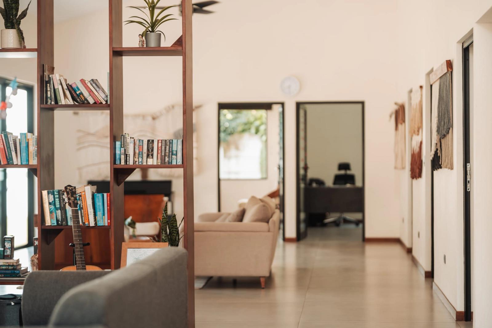 The living room at Atenas, with bookshelves, a guitar and a sofa, and a hallway to the offices.