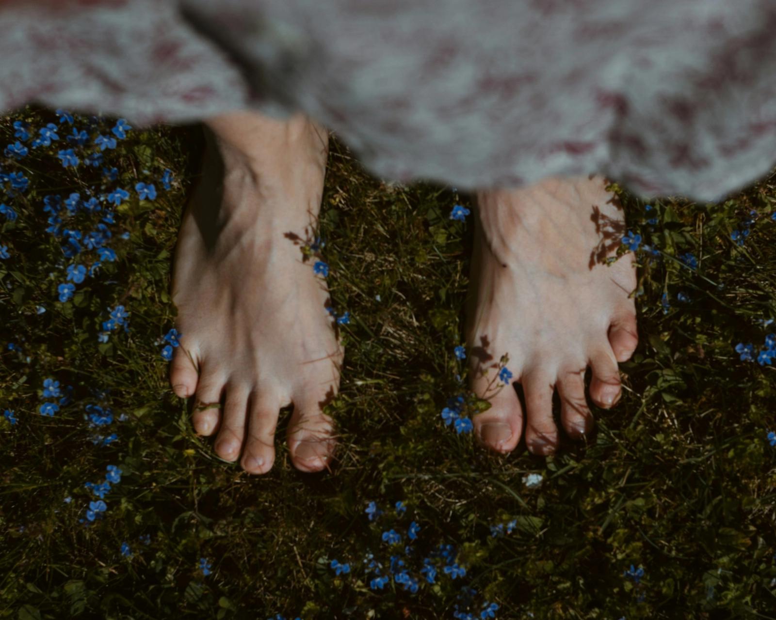 Bare feet resting on soft green grass.