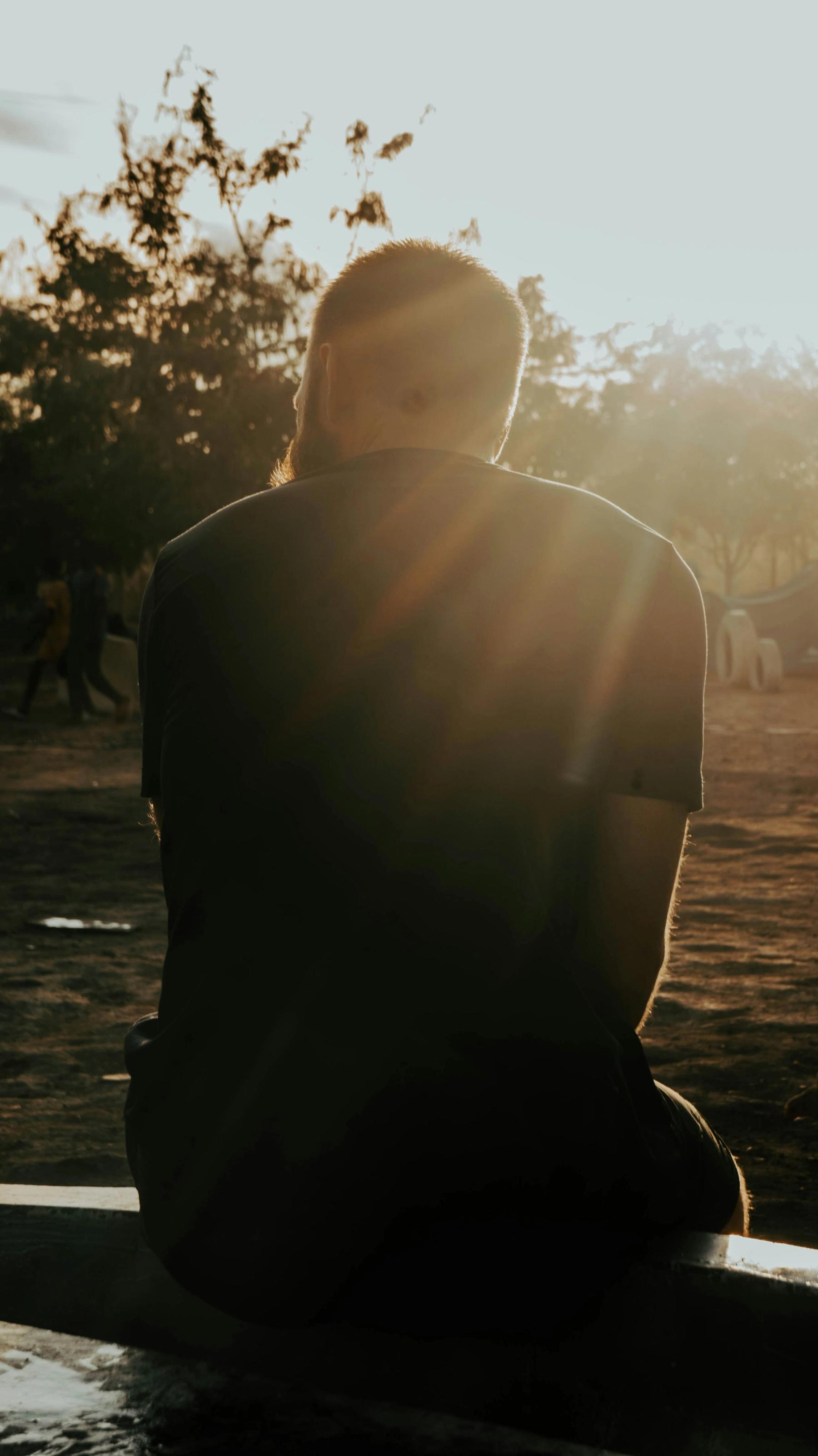 A person sitting quietly on a bench in warm sunlight.