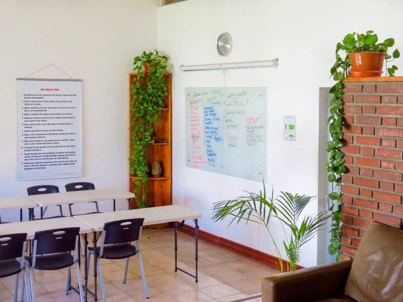 Group session room at the San José residence with worktables, a whiteboard and a Twelve Steps poster on the wall.
