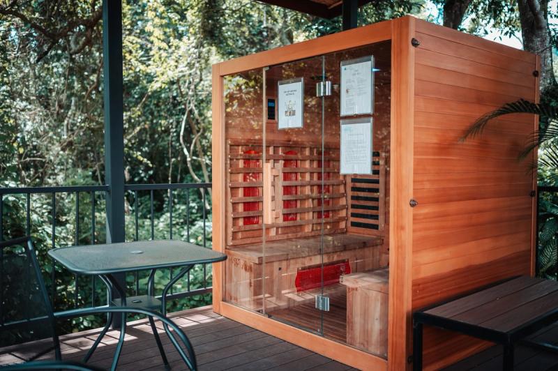 The infrared sauna on a covered deck at Atenas, beside a small table and the forest.