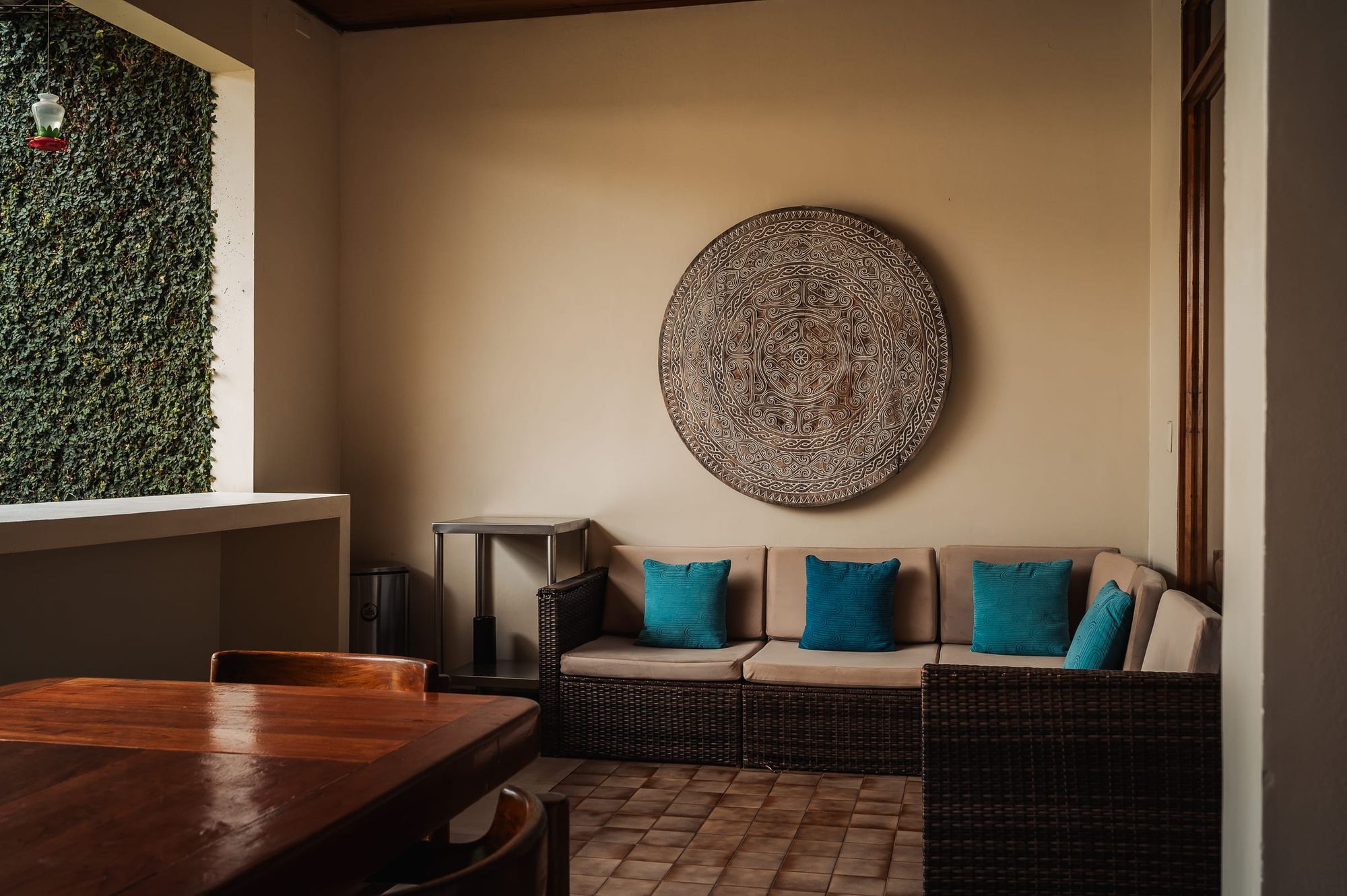 A corner lounge at San José with blue cushions, a woven wall disk and a green wall.