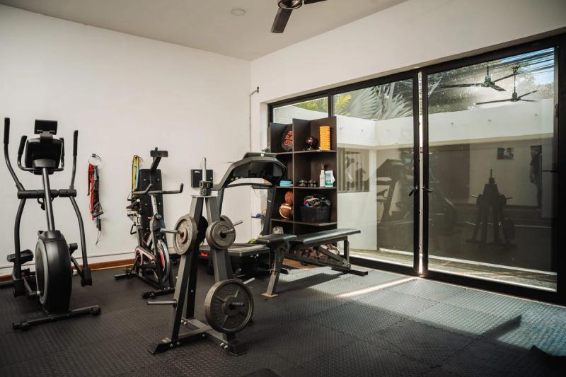 The gym at San José, with cardio machines and a rack in front of glass doors.