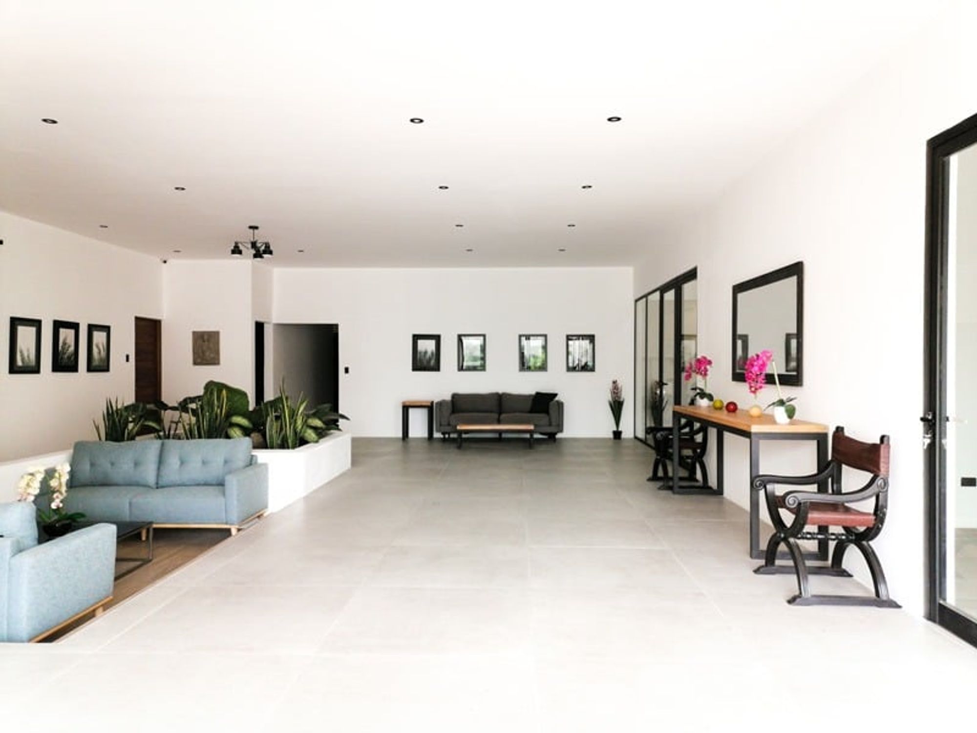 Bright sala at the San José residence, with pale-blue sofas, framed art on white walls and a planted atrium.