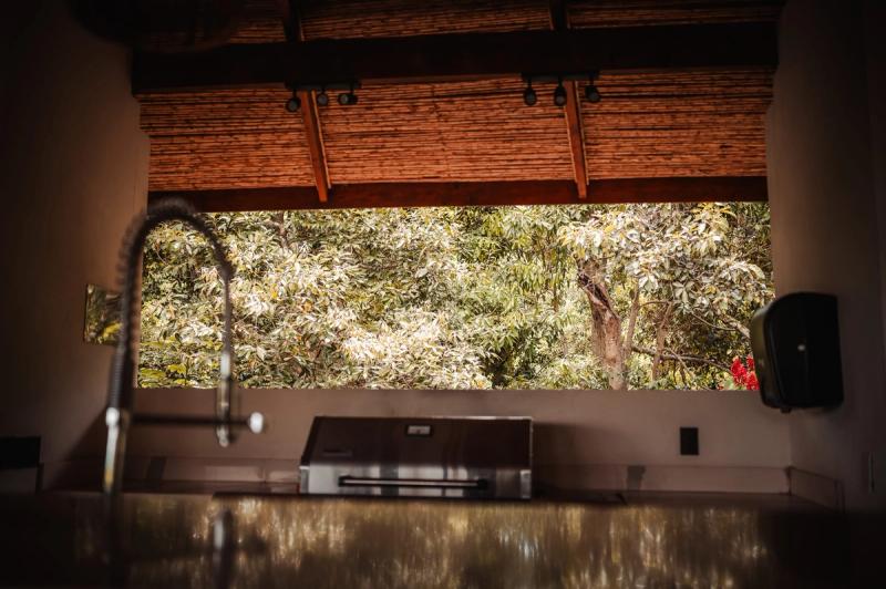 An open-air kitchen counter under a wooden roof, looking out to the trees.