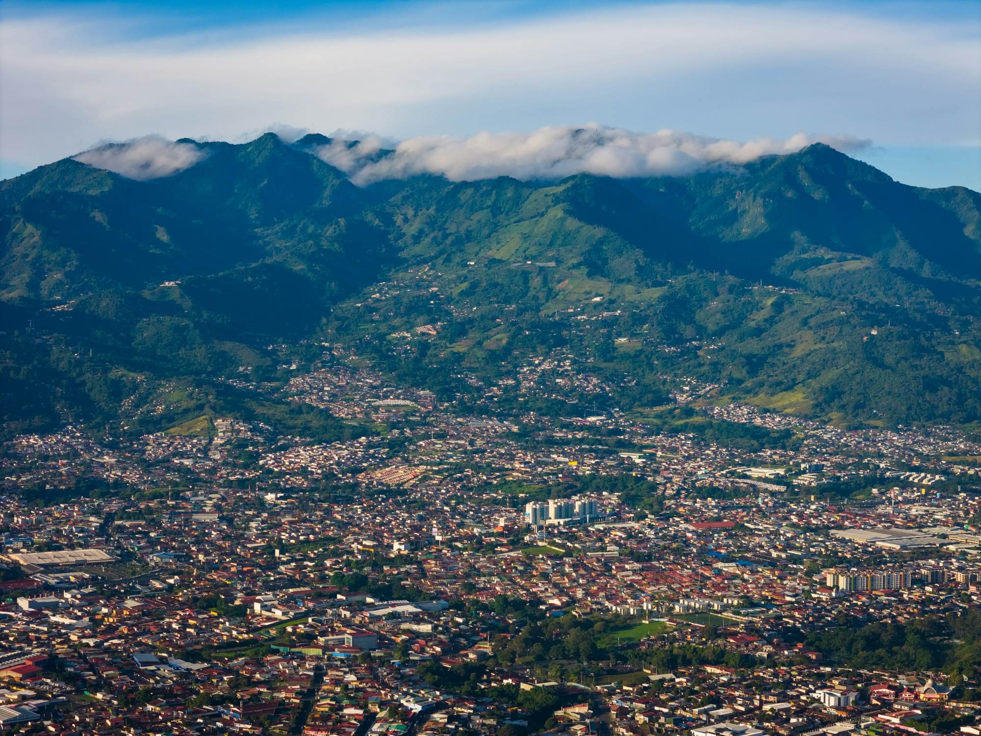 An aerial view of a city with the mountains of the Central Valley rising in the background.