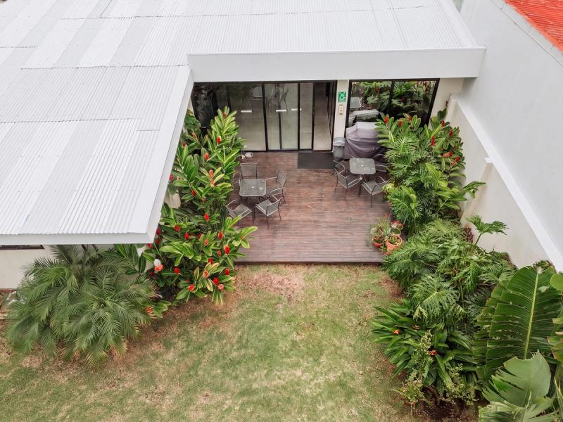 An aerial view of the San José residence's enclosed courtyard, with tables on a deck and a lawn ringed by plants.