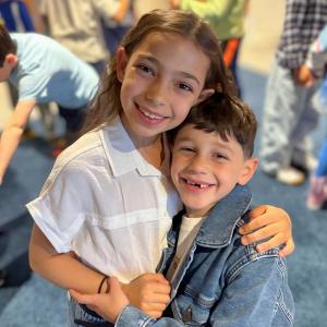 Two Israeli Senesh students smiling and hugging each other.