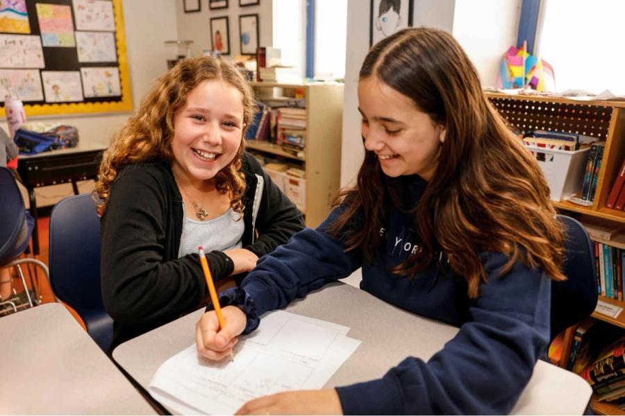 Two Senesh middle school students study together while smiling.