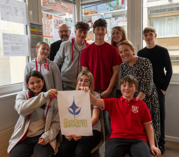 ISS primary and secondary students with their teachers, holding a student-designed poster
