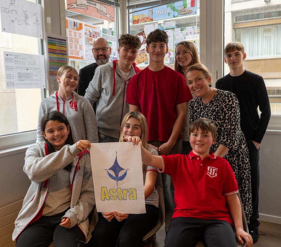 ISS students of all ages with their teachers, holding a student-designed poster