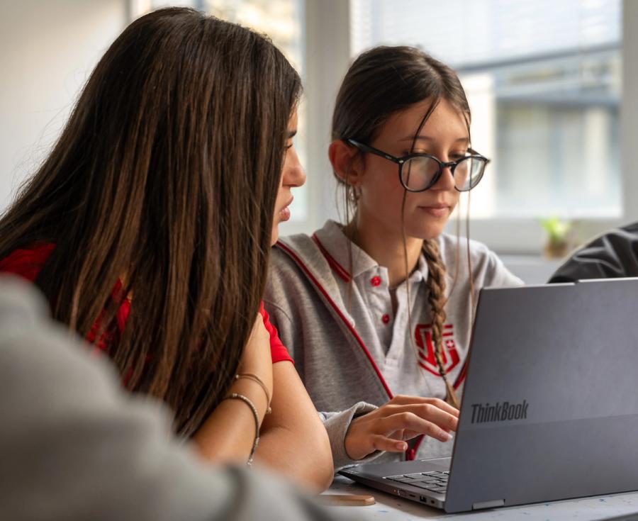 Two ISS students in school uniform working together on a laptop in class