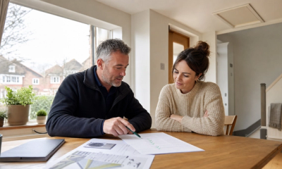 A UK homeowner and energy advisor reviewing an energy saving materials quote in a bright home.