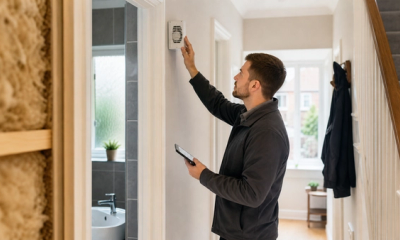 Retrofit assessor checking a home ventilation grille during an energy efficiency survey in a UK house.