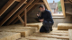 A UK energy assessor checking loft insulation during a Warm Homes Local Grant home survey.