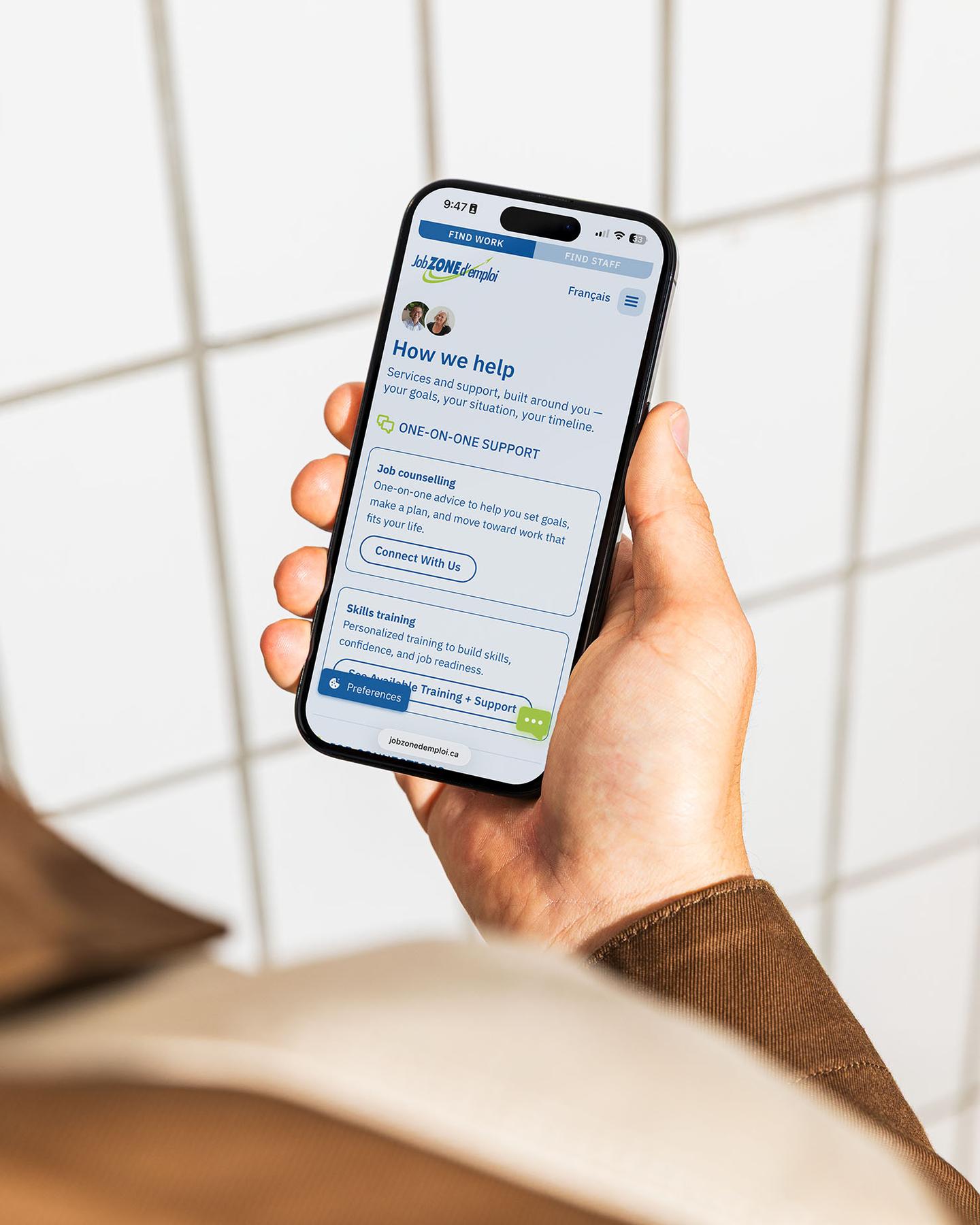 Person holding a phone looking at the Job Zone d'emploi website, which describes their services and how they can help.