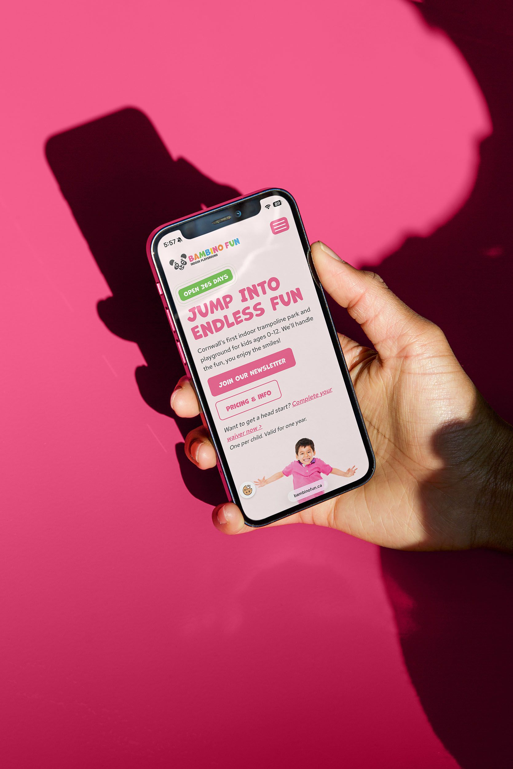 Person holding a phone with the Bambino Fun website home page open with text that reads "Jump into endless fun"