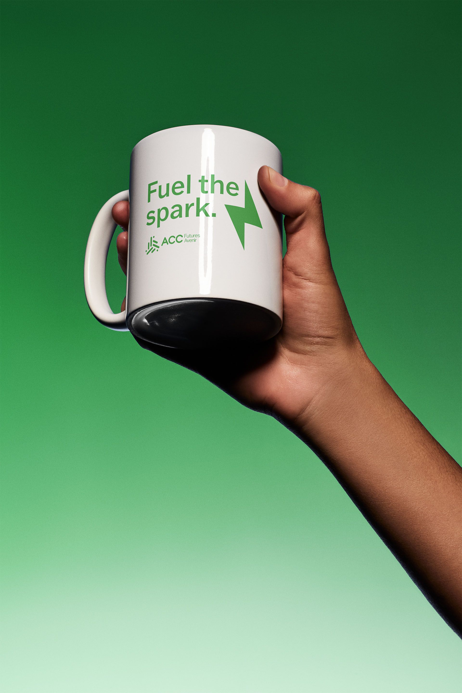 Person holding a white mug with text that says "Fuel the spark." with the ACCFutures logo and lightning bolt.
