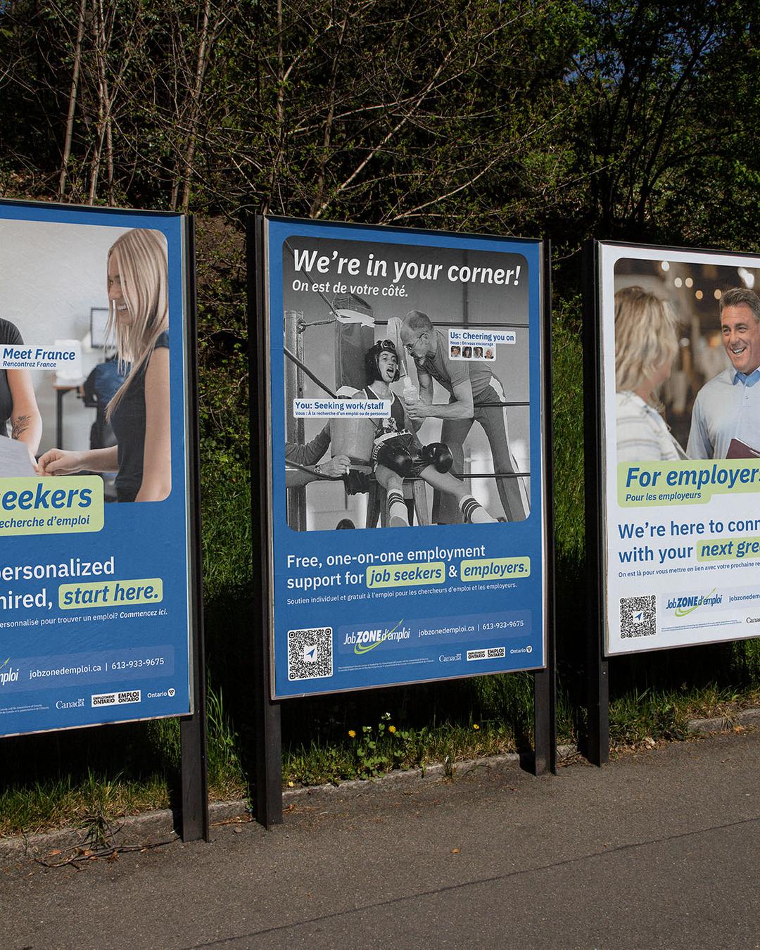 Exterior posters for job zone d'emploi featuring one for job seekers, one for employers, and one in the middle that says we're in your corner and has a visual of a coach and a boxer in their boxing ring corner.