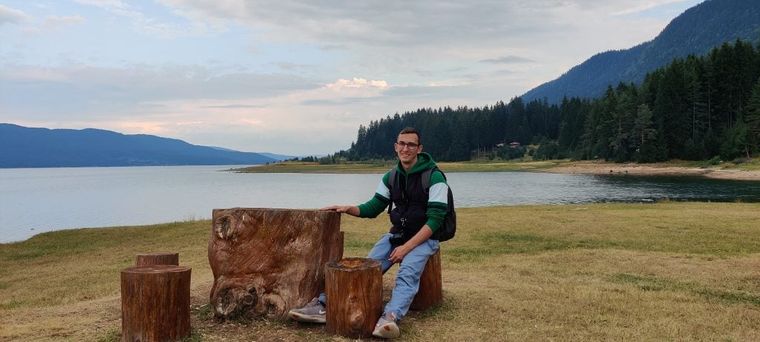 A happy man sitting near a lake