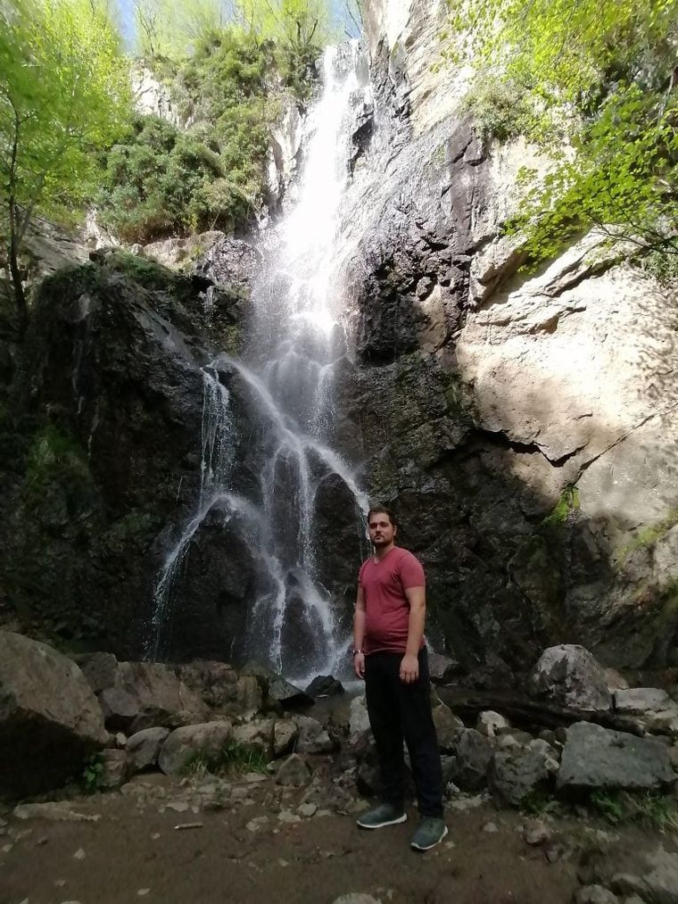 young-man-standing-infront-of-a-waterfall