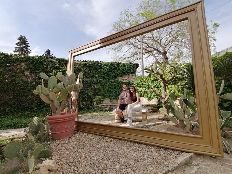two-smiling-people-in-a-picture-frame-in-a-garden