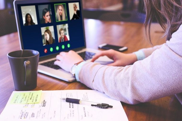 Woman's hands writing on laptop keyword with a cup and paper block next to her