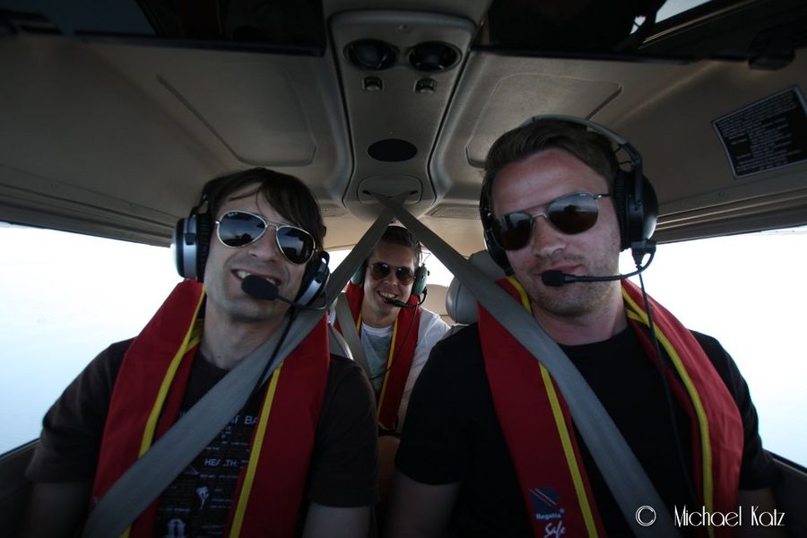 Selfie tatt forfra og bakover i flyet. Tre fornøyde karer med redningsvesten på.