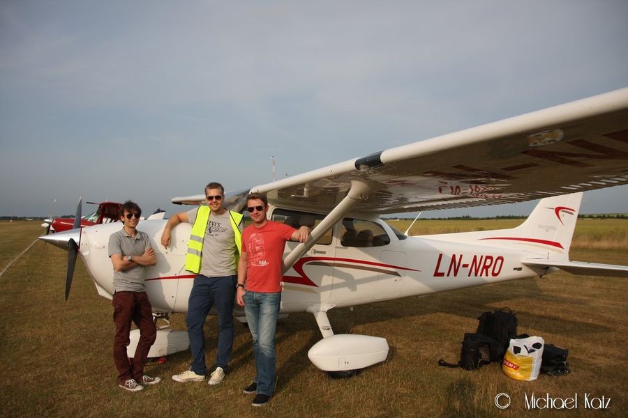 Mannskap poserer foran parkert fly på gresset på Duxford Airfield
