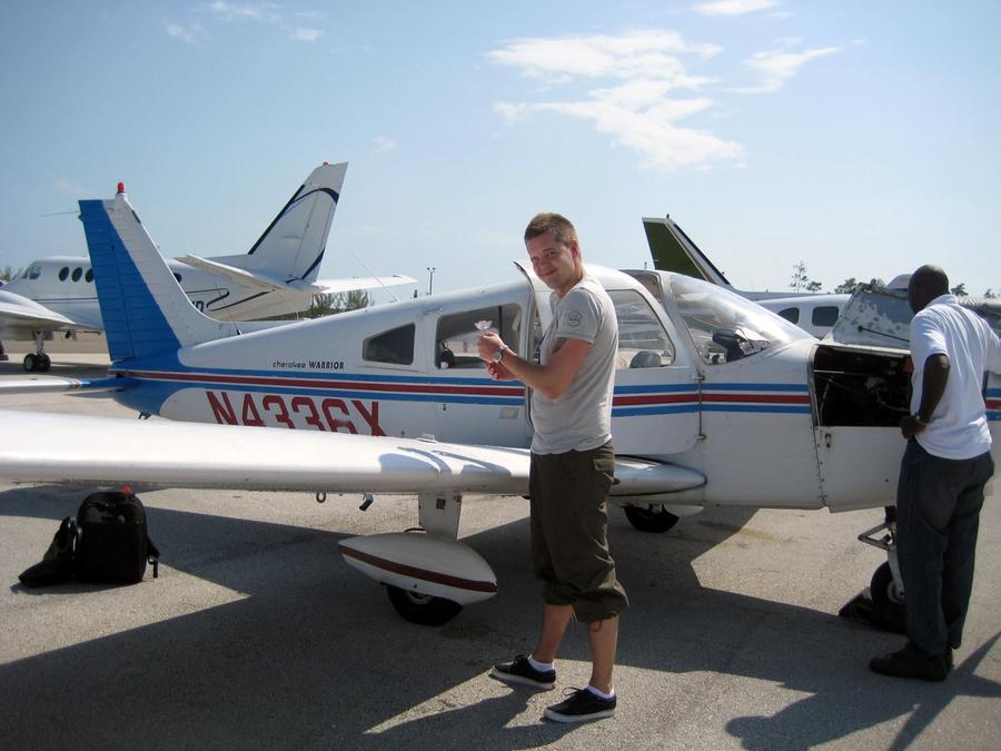Pilot foran en hvit Piper Cherokee med blå og røde striper