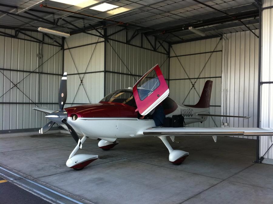 Rødt og hvitt småfly i hangar