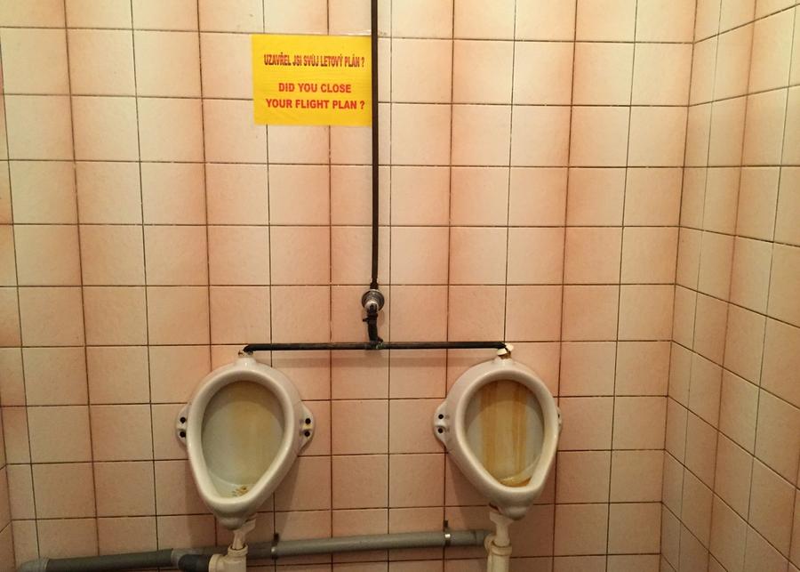 Skilt, hengende over urinal, med teksten: Did you close your flightplan