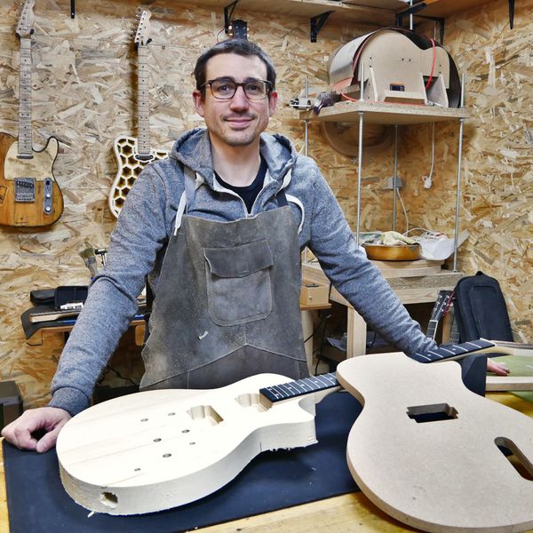 Photo du luthier Vincent Brun dans son atelier de fabrication. Il est devant une guitare type lesPaul en cours de fabrication