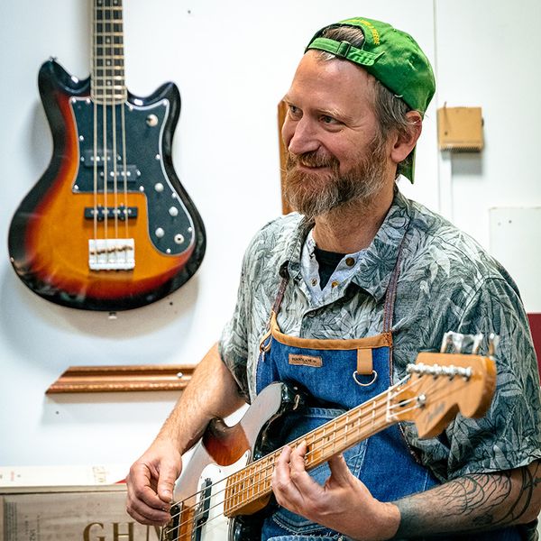 Photo du technicien guitares Jérôme Rabetaud jouant de la basse dans  son atelier