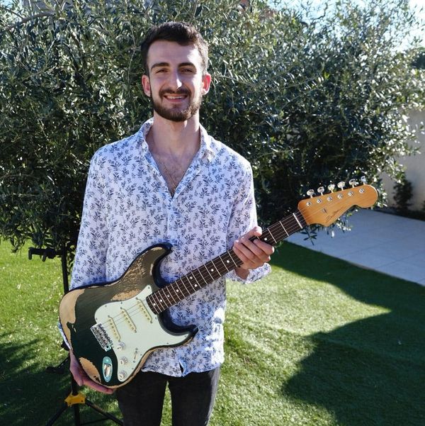 Photo du formateur Hugo Mikikian en extérieur pourtant une stratocaster noire.