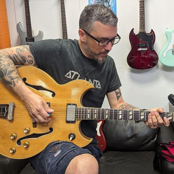 Photo du technicien et musicien Sofienne Yahiaoui jouant une Gibson Barney Kessel dans l'atelier Atlanta Formations