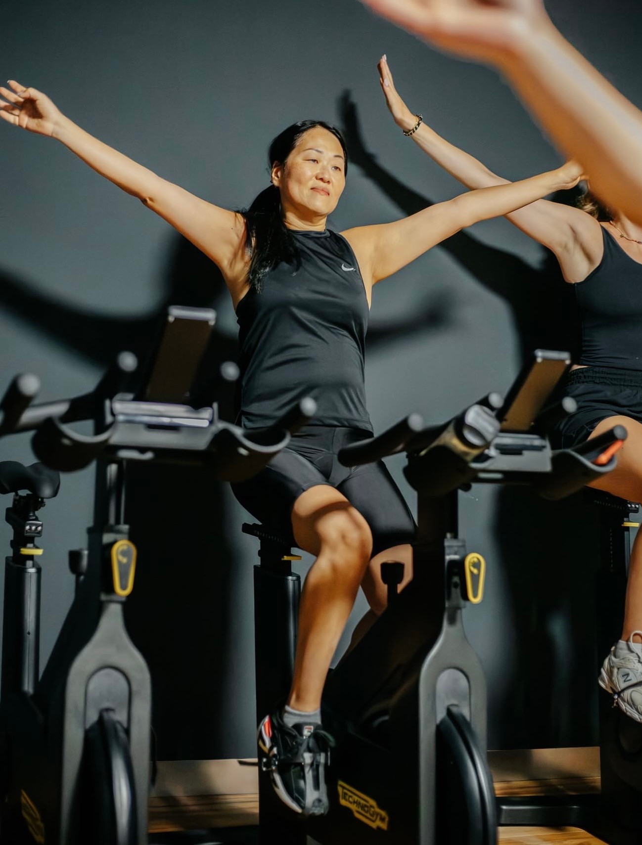 Indoor cycling class in pink light, bikes lined up in rows