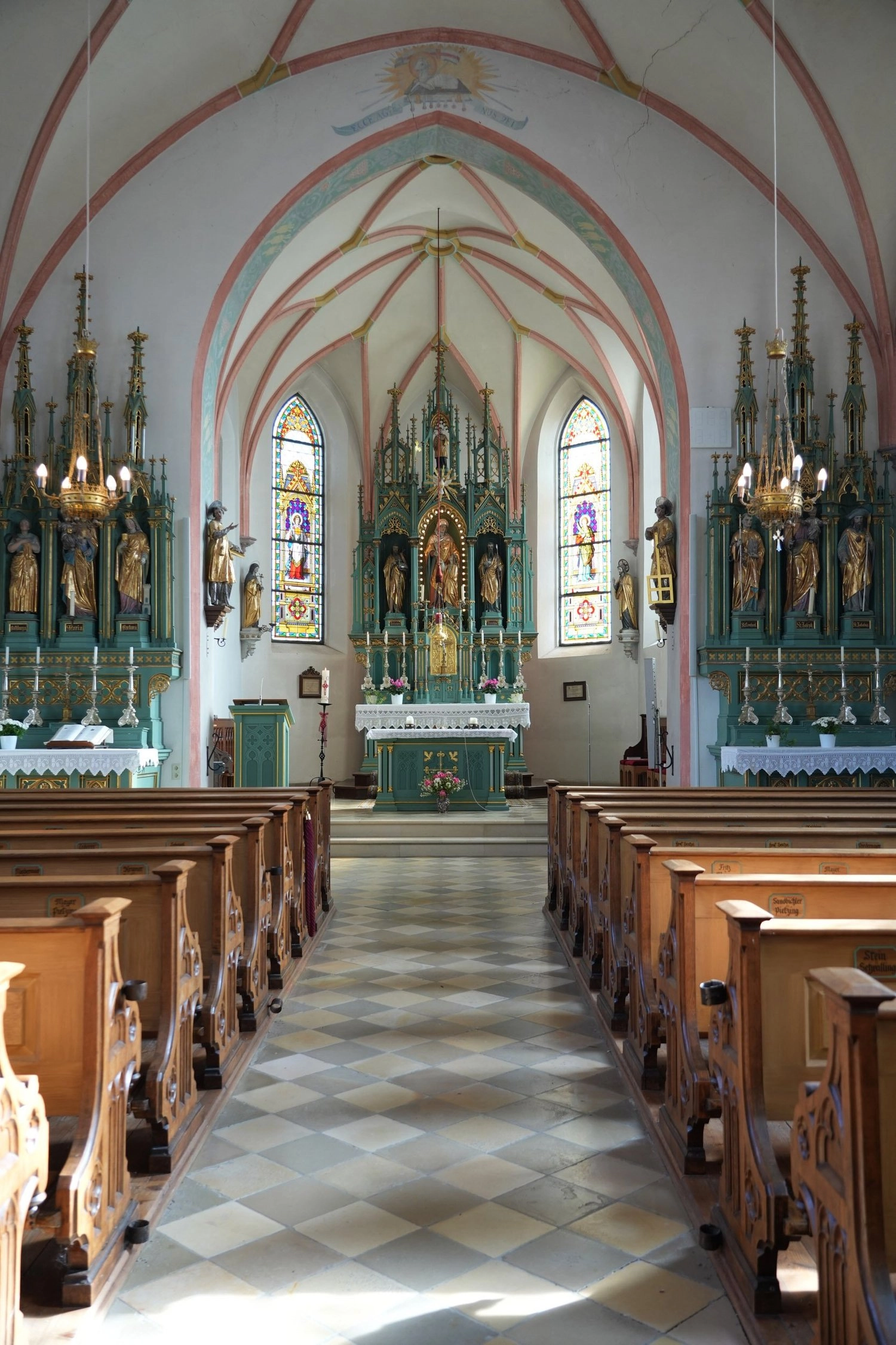 Der Blick führt durch hölzerne Kirchenbänke zum geschmückten Altar.