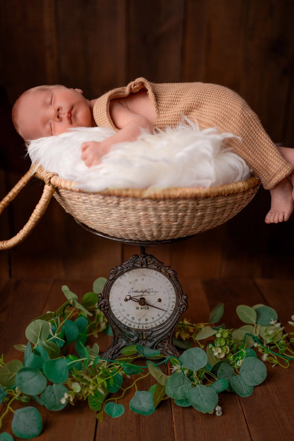 Ein schlafendes Baby liegt im gepolsterten Korb auf einer nostalgischen Waage.
