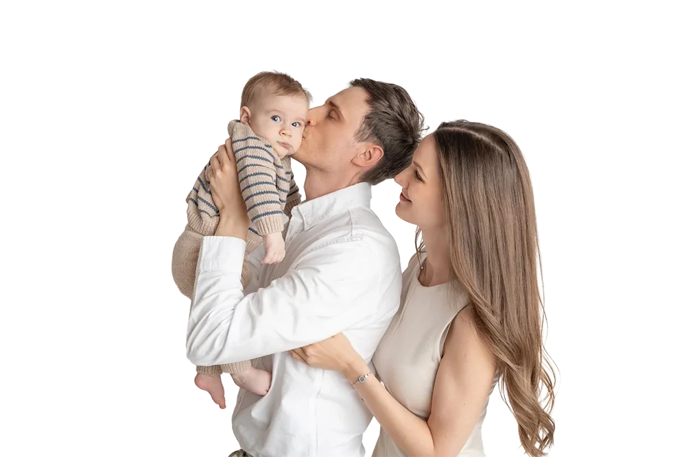 Ein Mann küsst sein Baby, während eine Frau lächelnd danebensteht.