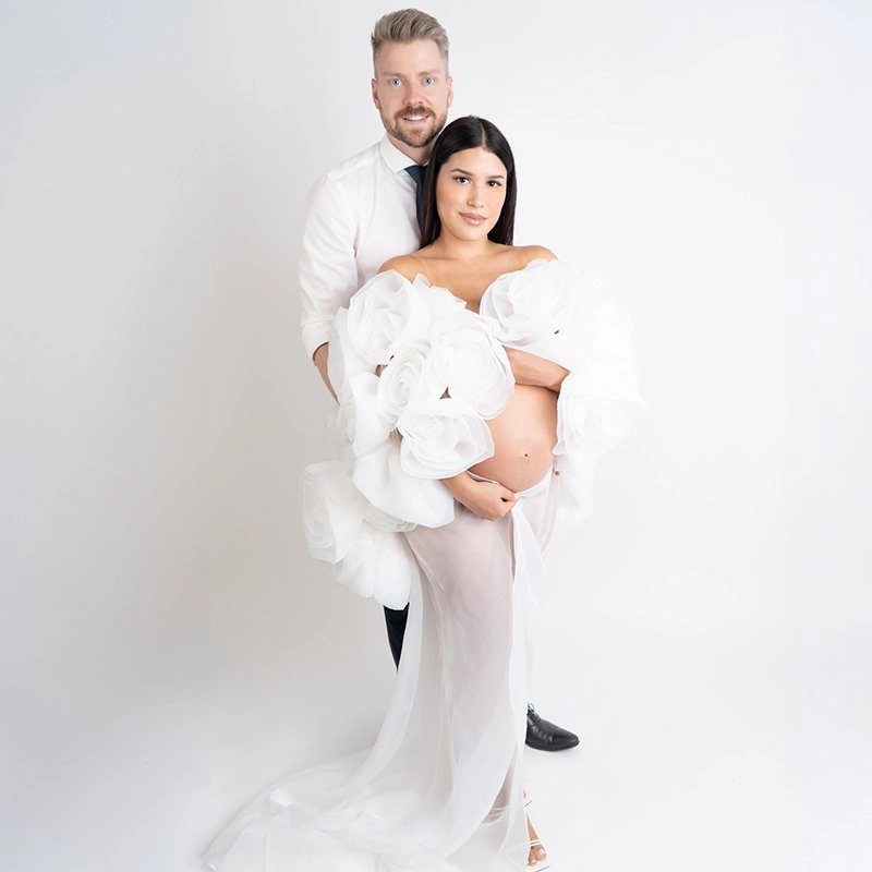 Ein Paar steht in weißer Kleidung zusammen und hält den Babybauch.