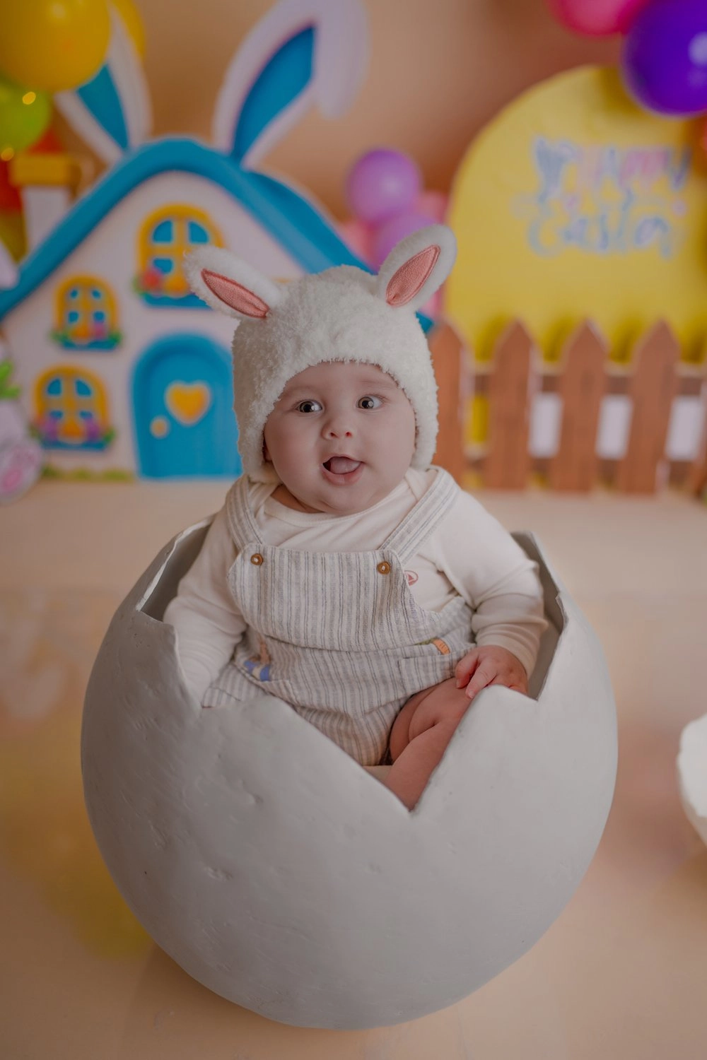 Ein Baby mit Hasenmütze sitzt in einem aufgebrochenen weißen Dekoei.