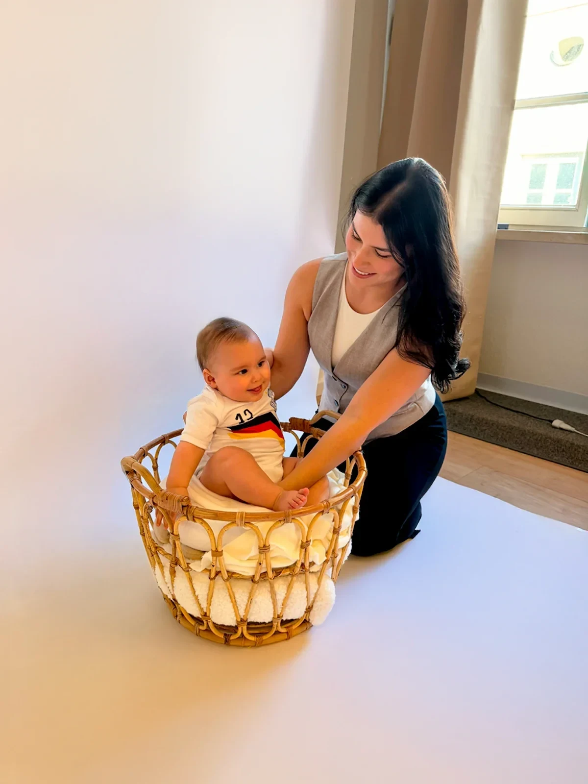 Eine Fotografin kniet neben einem Baby und begleitet es im Korb.