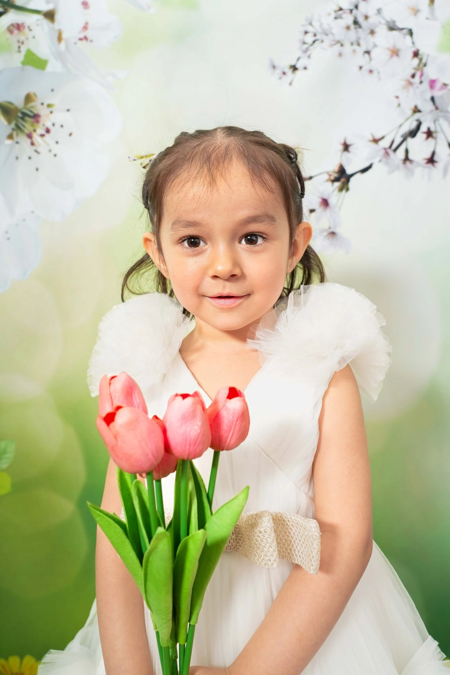 Ein Kind im weißen Kleid hält einen Strauß rosa Tulpen.